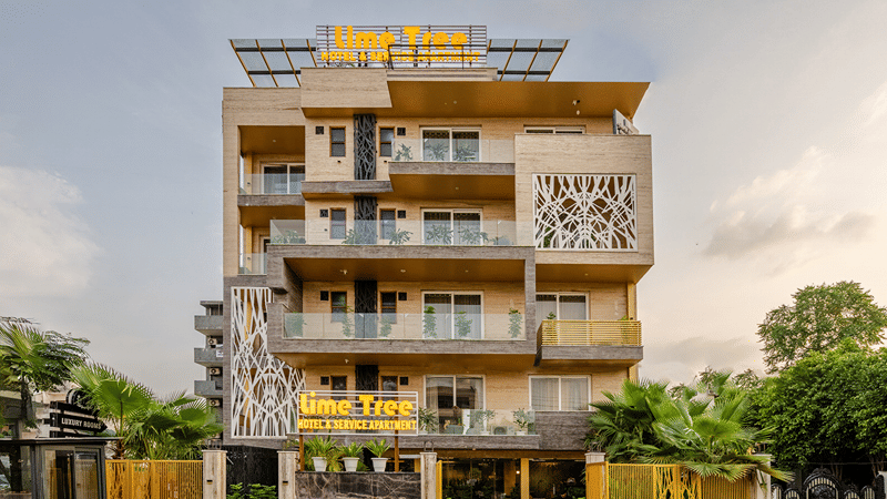 Multiple storey facade of Lime Tree Hotel Near Medanta-The Medicity, Gurgaon featuring an entrance with lawn leading to a building with balconies in each floor attached to the rooms