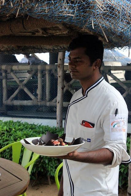 An image of a waiter standing with a food platter on his hand