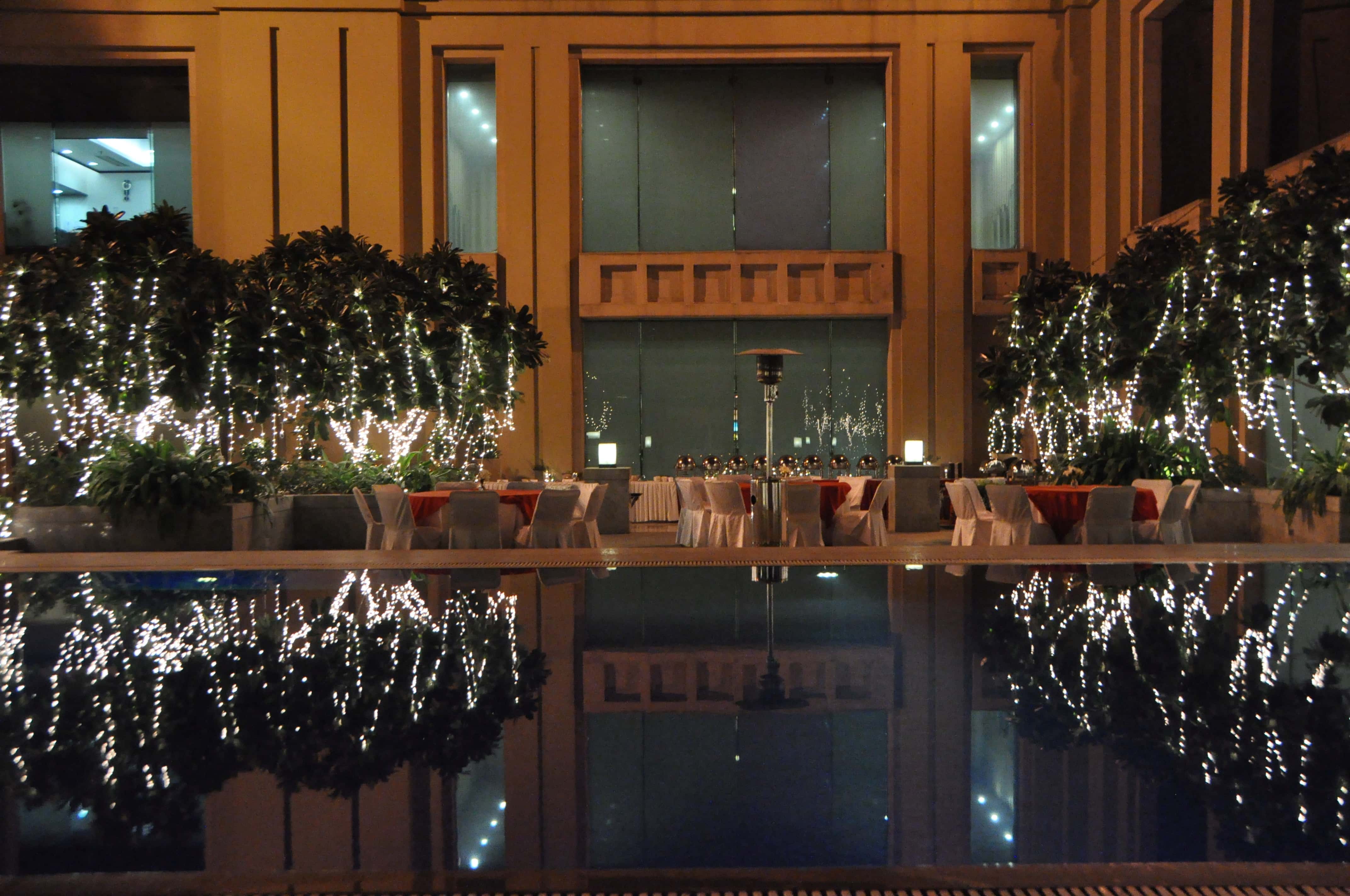The Garden of Joy by the pool, set for an evening event with tables and fairy lights