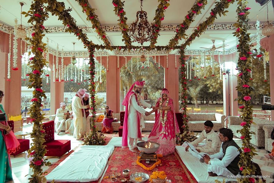 A bride and groom perform wedding rituals under a floral-adorned pavilion, surrounded by family and priests at a Luxury Destination Wedding Resort in Jaipur - Umaid Palace - A Lakeside Heritage Palace Resort
