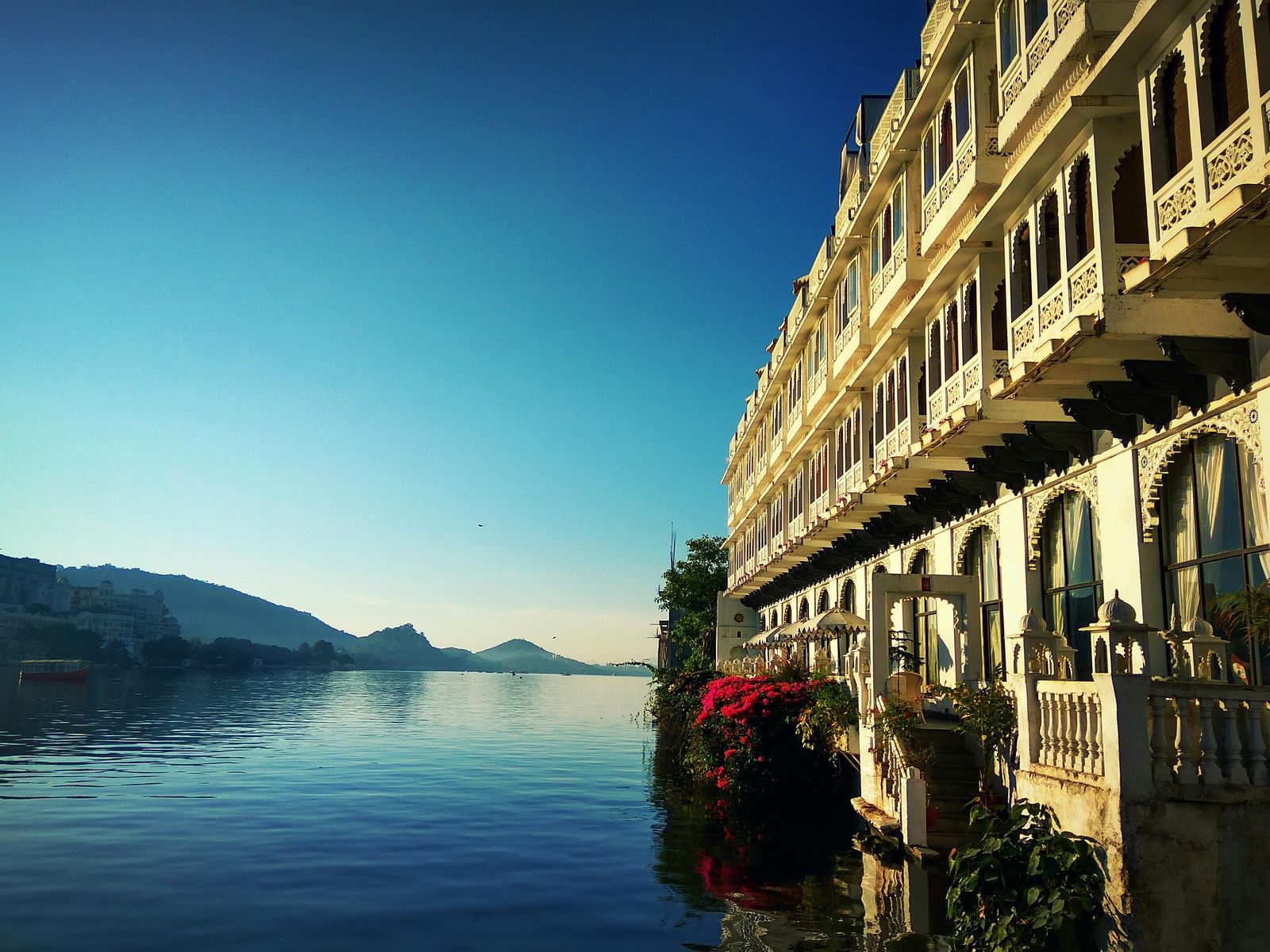 A lake view with mountains in the background and a building occupying half the frame in the foreground