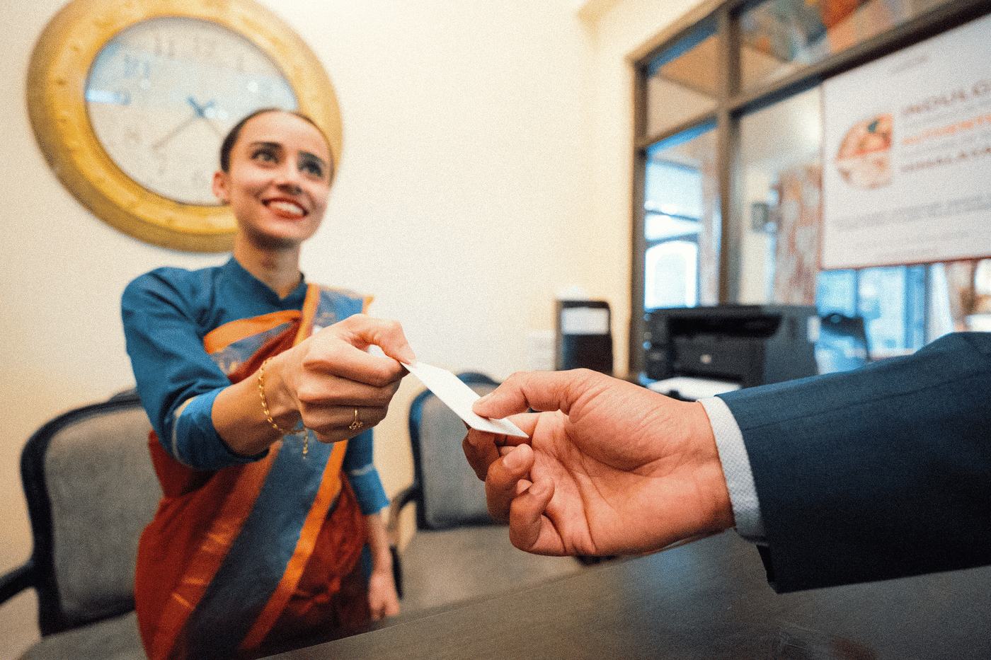A receptionist handing over the key card to her guest at the hotel.