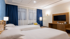 twin beds with a wall mounted tv inside Classic Twin Room - La Maison Hotel, Doha