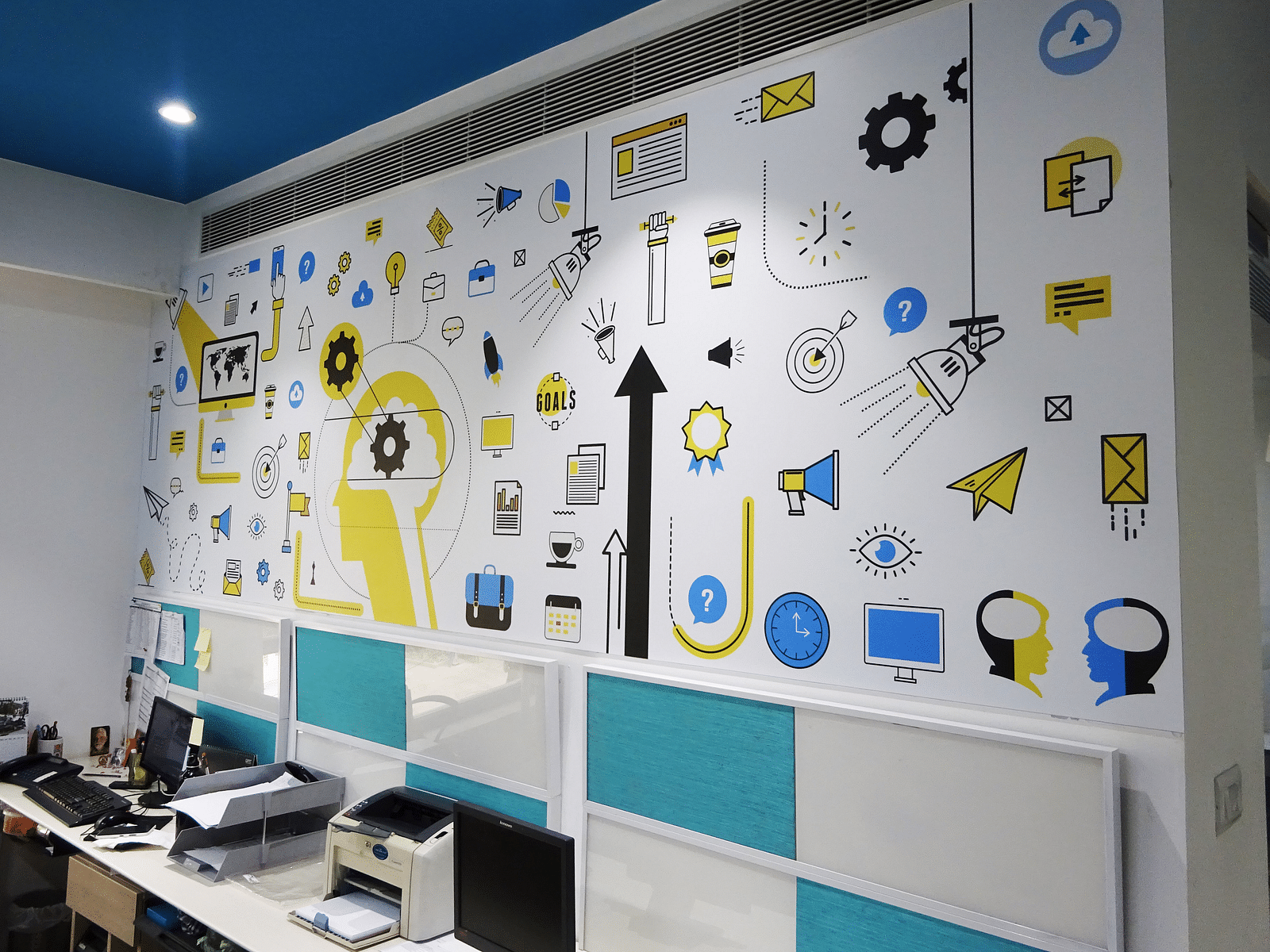 A office cabin view showing a chair and workspace with a designer wall in the backrgound.