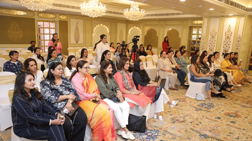 Group of women professionals posing in front of branding at a women-centric corporate event.