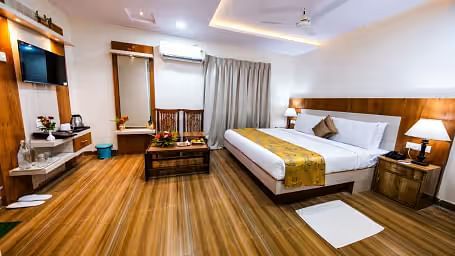  A spacious room with a large bed, wooden bedside tables on either side, and a wall-mounted television facing the bed.