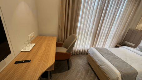 Deluxe Room with a large large bed, bedspreads, pillows, a wall framed art, and a large window at Hotel Mumbai House Mindspace, Malad.