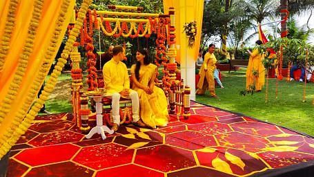 A couple sitting for a haldi function in a mandap in the lawn area of Swosti Resorts