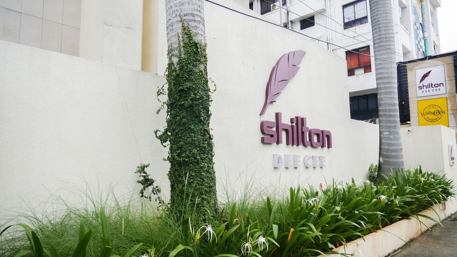 The exterior entrance of a building with a sign featuring a feather logo and the name 'Shilton' | Shilton Hotels