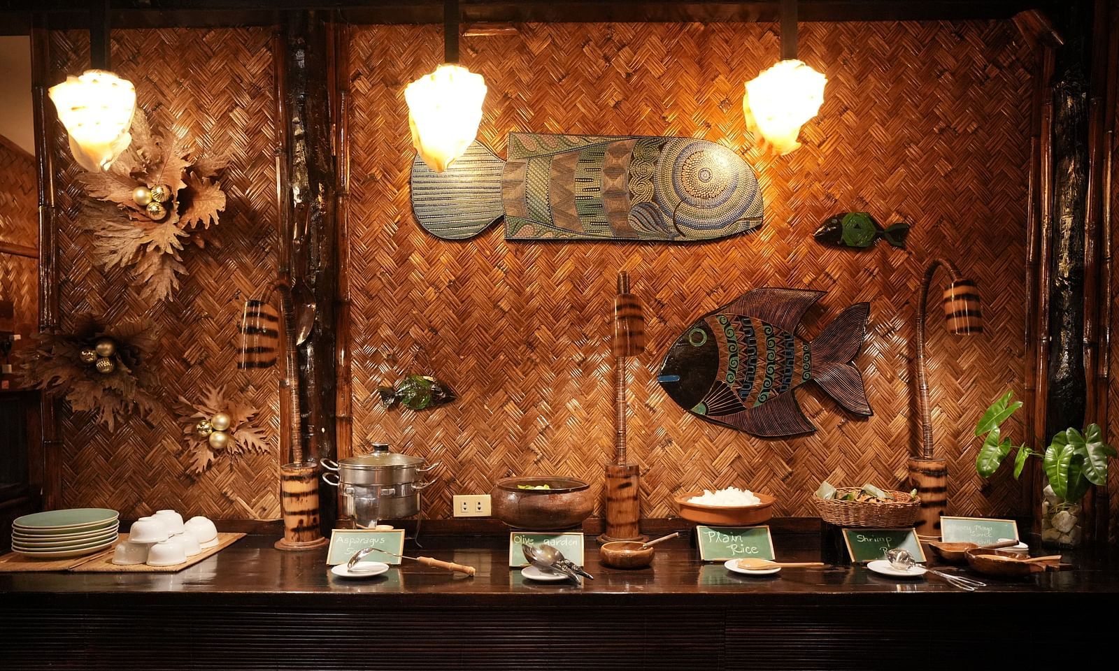 Indoor dining space at Flower Island Resort with fish-shaped wall decor, wooden furniture, and overhead lighting.