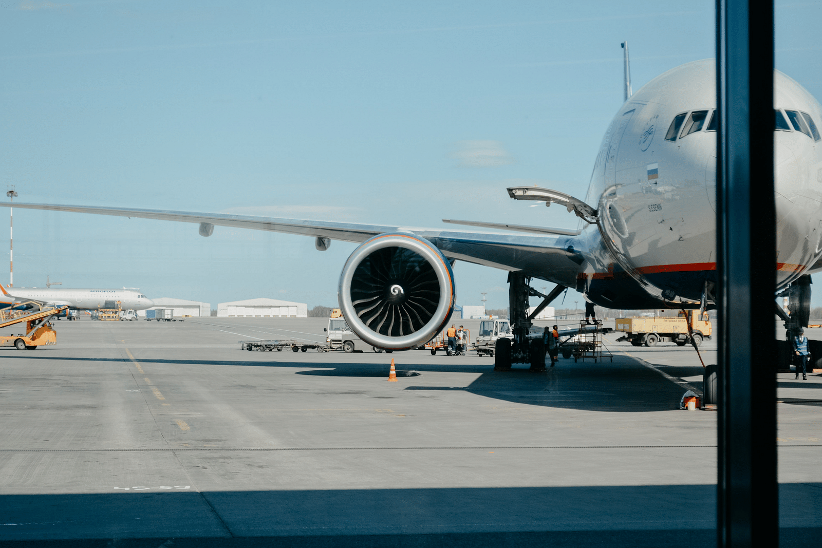 An aeroplane parked in an airport as seen from inside the terminal.