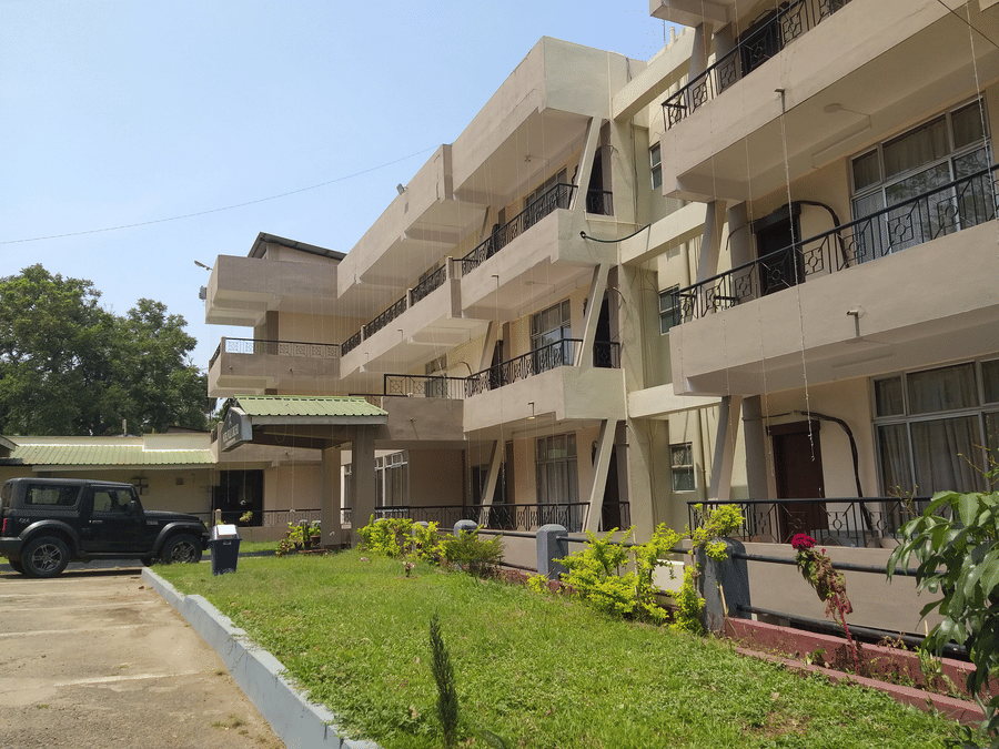 A view of the Polo Tura Hotel from a corner, showing its balconies, with a vehicle parked in front.
