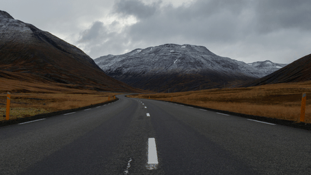 An overview of a highway with single lanes on either side and a mountain in the background.
