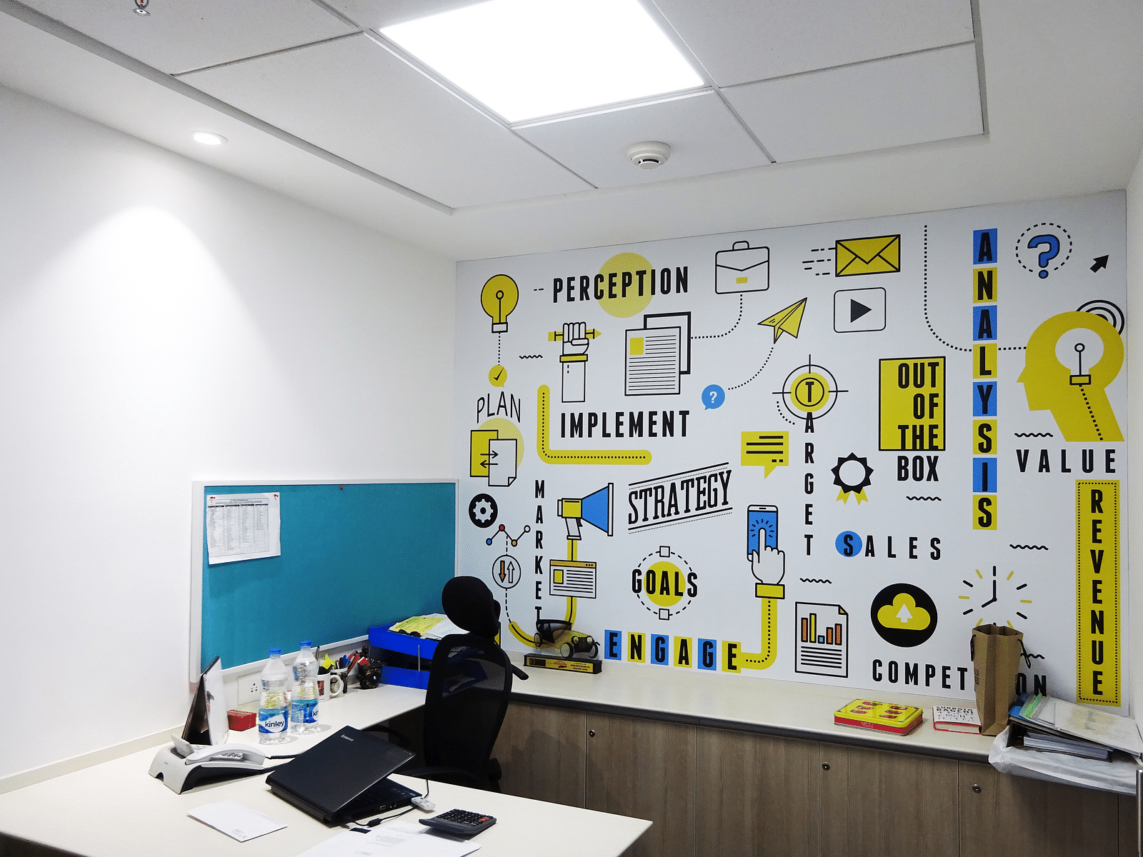 A office cabin view showing a chair and workspace with a designer wall in the backrgound.