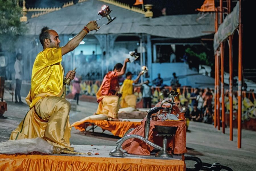 Priests worshipping in the open area decorated with flowers and other worship items.