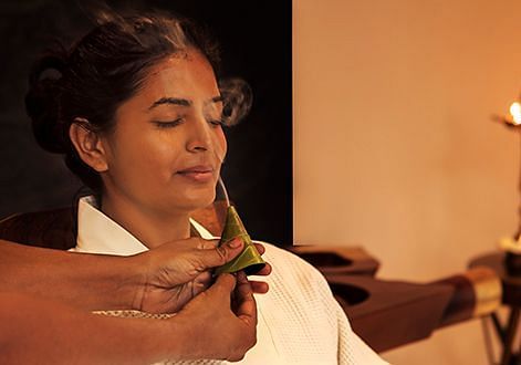 A person holding a small object near lit candles, warm lighting - Shreyas Retreat