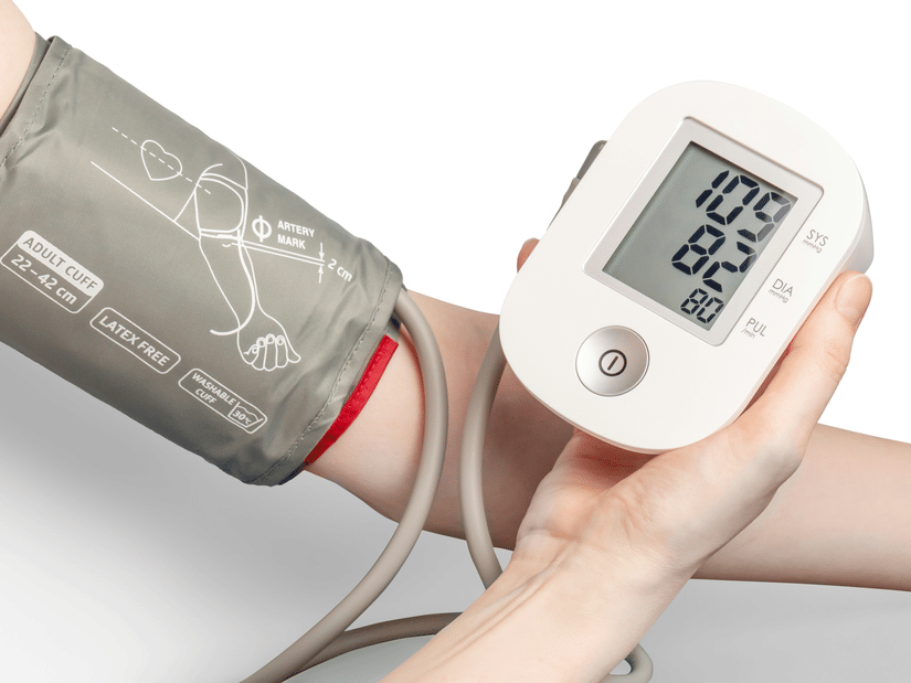 A digital blood pressure monitor cuff fastened on a person's arm, showing a reading
