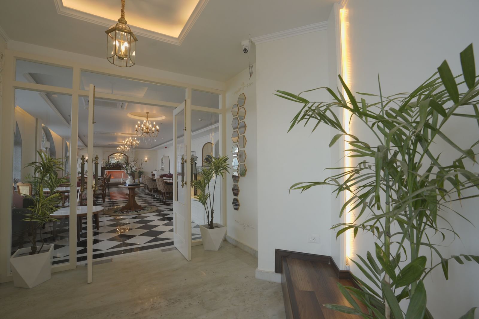 Glass entrance with ambient evening lighting and potted plants - Mayfair Cafe & Suites, Dalhousie
