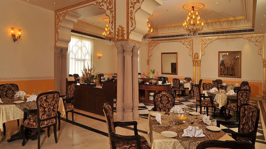 Image of a dining space with tables and chairs and intricately designed pillars and walls at Rajasthali Resort & Spa Jaipur.
