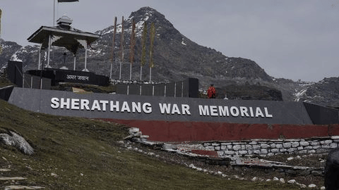 Sherathang War Memorial in Ladakh set against rugged mountains, honoring Indian soldiers with a stone monument and flags.
