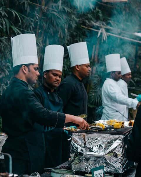 Chefs in uniform preparing food at an outdoor cooking station at Karma Chalets.