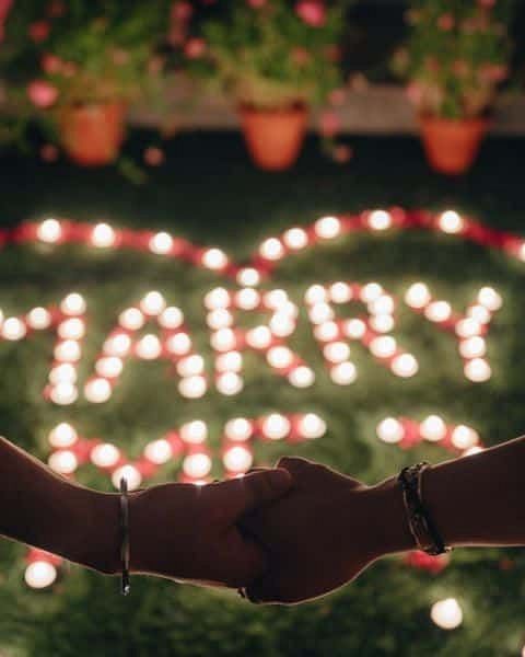 Close-up of hands in front of a light display reading “MARRY” at Karma Chalets.
