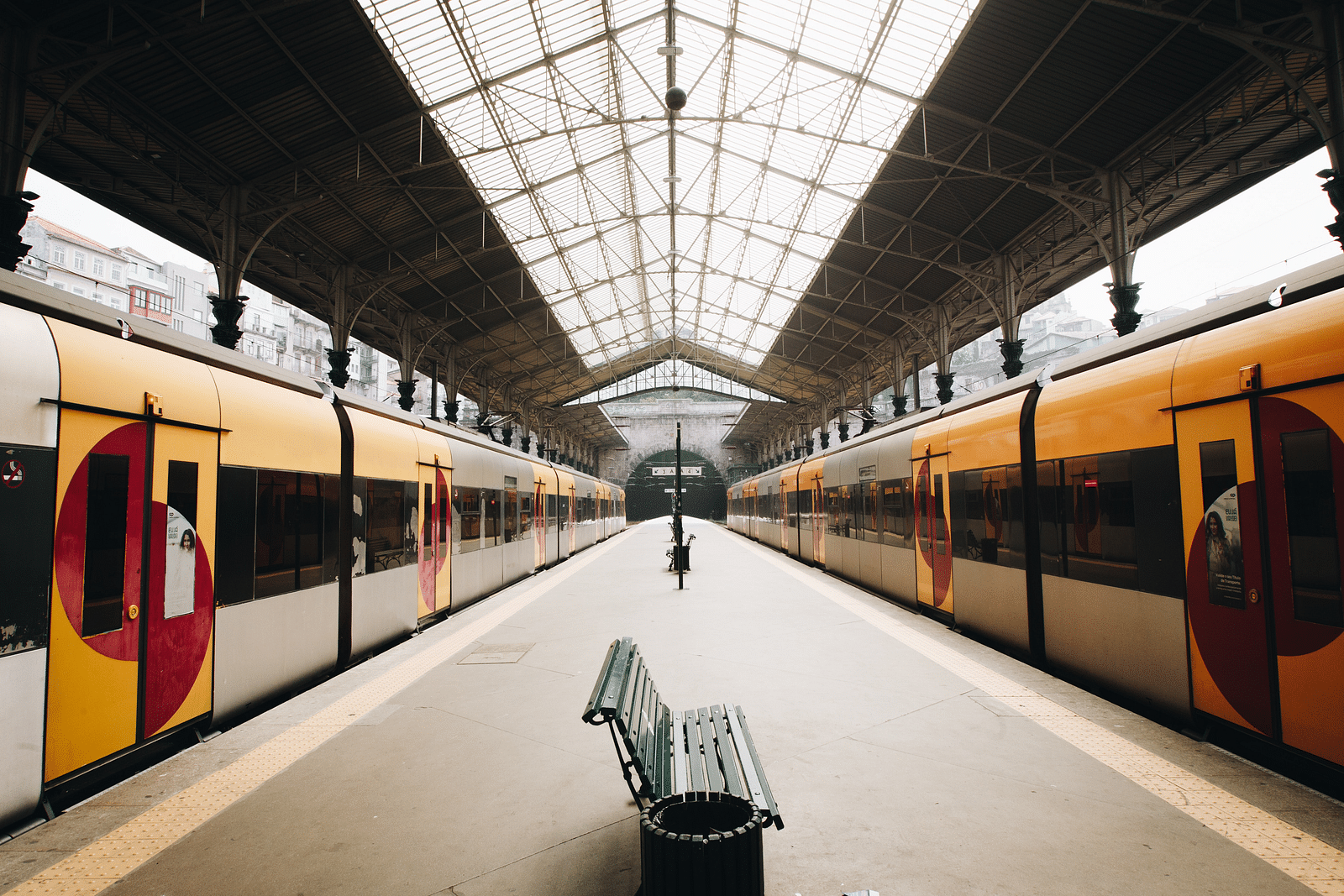 A train station with a platform in the centre and trains on either side of it.