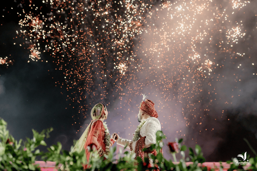 Bride and groom celebrating under fireworks during a night wedding event.
