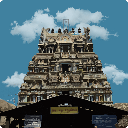 A gopuram of a South Indian temple rises majestically against a bright blue sky with scattered clouds.