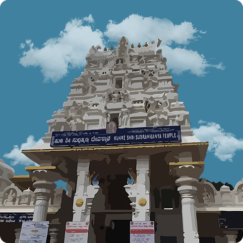 A white temple entrance with a multi-tiered gopuram, and a sign in a local language, under a blue sky.