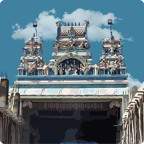 The intricate, detailed top of a temple gopuram featuring colourful sculptures and carvings.