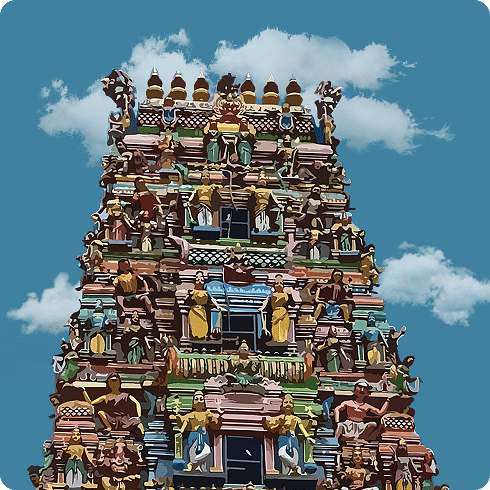 A vibrant gopuram of a South Indian temple stands tall, adorned with detailed carvings and bright sculptures.
