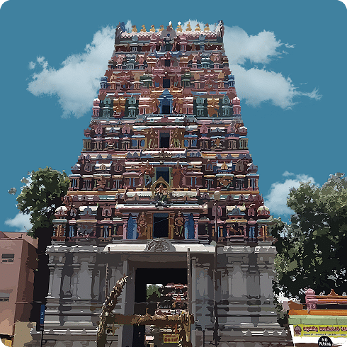 The multi-coloured, towering gopuram of a temple against a clear, blue, cloudy sky.
