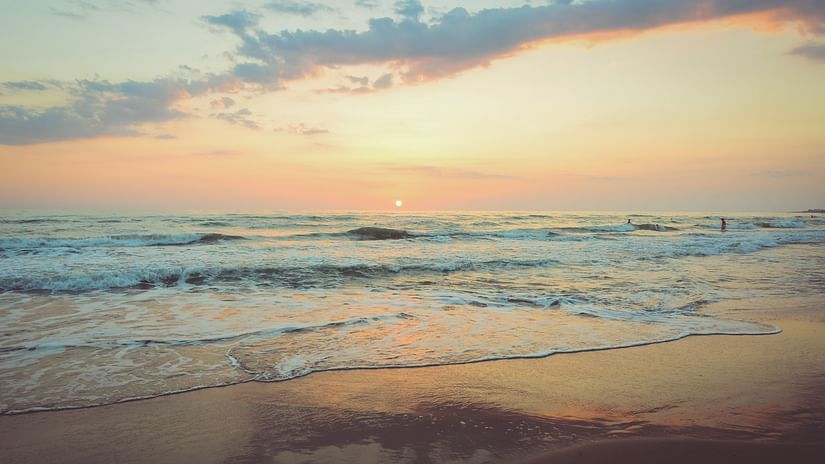 Waves overlapping on the beach with the setting sun in the background.