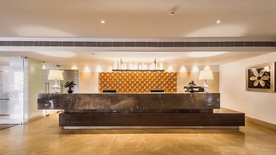 A modern hotel reception area with a large golden art piece behind the desk and elegant lighting - TGI Grand Fortuna, Hosur