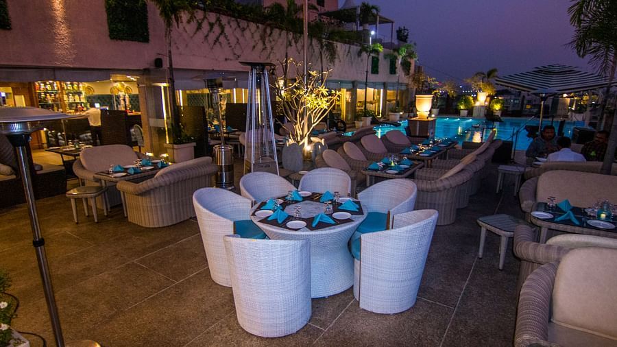 A eating area with white chairs around a small, round table with a blue centrepiece at Hotel Ashok Nagpur.