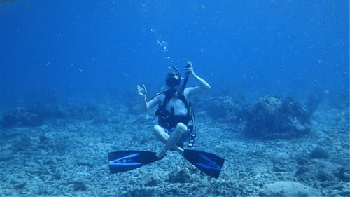 A diver pretending to sit cross-legged on the seabed