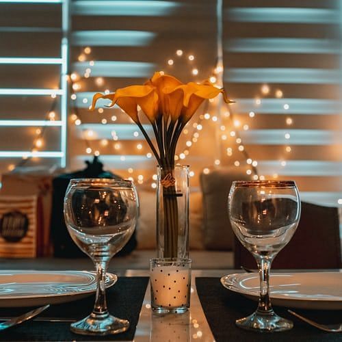 two wine glasses kept along with a vase of flowers