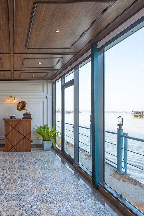 Glass-enclosed corridor at Polo Floatel Kolkata with tiled floor and river-facing windows.