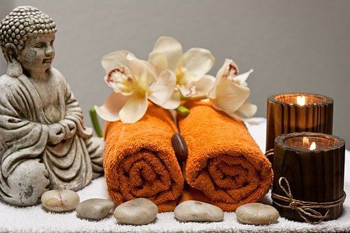 Image of towels beautifully wrapped and placed next to a candle and a miniature statue of Lord Buddha