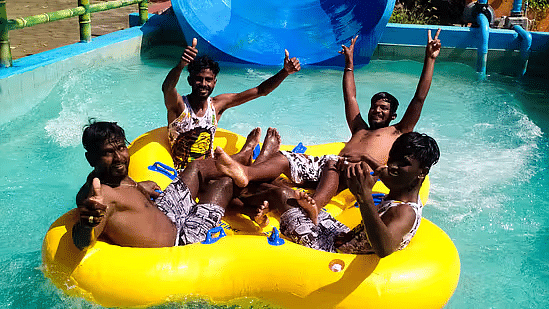A group of friends laughing and riding a yellow inflatable raft down a water slide - Black Thunder Water Theme Park