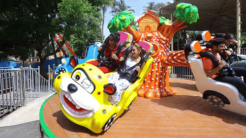Children enjoying a cartoon-themed kiddie ride at Black Thunder amusement park with colorful decor