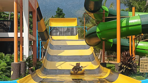 The top of a tall, yellow and green multi-lane water slide with steps leading up - Black Thunder Water Theme Park