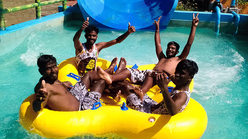 A group of people laughing and enjoying a water ride in a large yellow inflatable tube at Black Thunder - Water Theme Park.