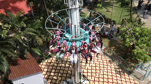 Thrill ride at Black Thunder amusement park with guests elevated high into the air surrounded by palm trees