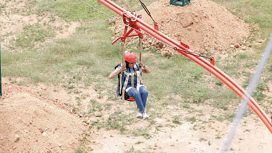 Woman enjoying the Zipline Coaster ride with a safety helmet at Black Thunder, showcasing the park’s thrilling adventure experience