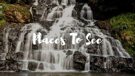 A cascading waterfall surrounded by lush greenery, highlighting scenic natural attractions to explore.