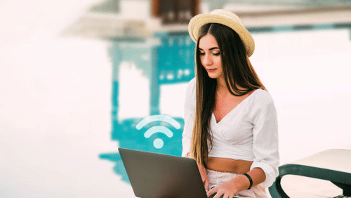 A girl working on her laptop by the pool.