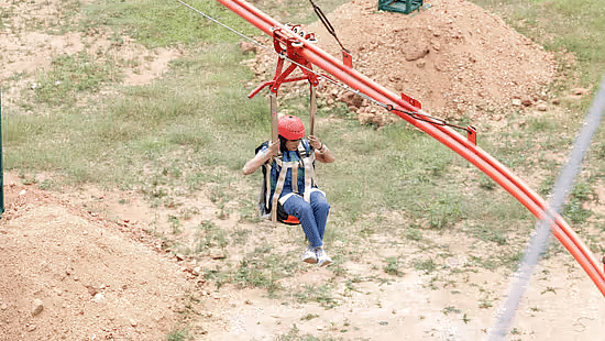 Woman enjoying the Zipline Coaster ride with a safety helmet at Black Thunder, showcasing the park’s thrilling adventure experience