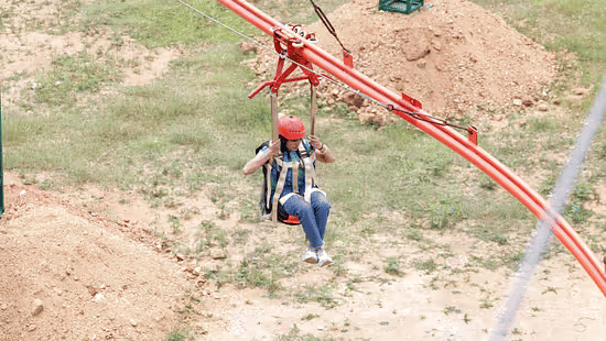 A Woman enjoying the Zipline Coaster ride with a safety helmet at Black Thunder, showcasing the park’s thrilling adventure experience.